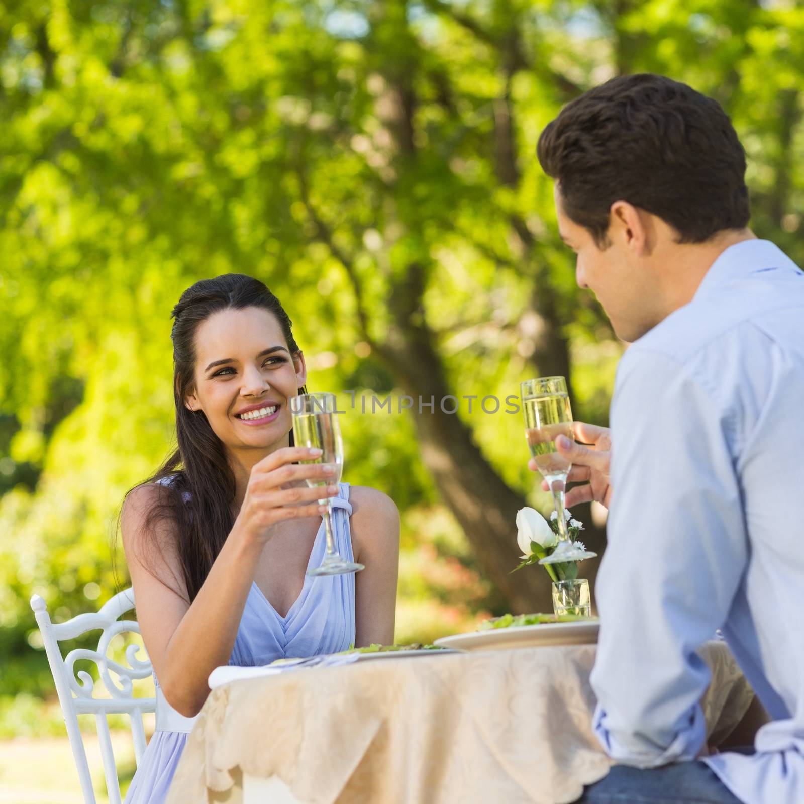Smiling young couple toasting champagne flutes at an outdoor café