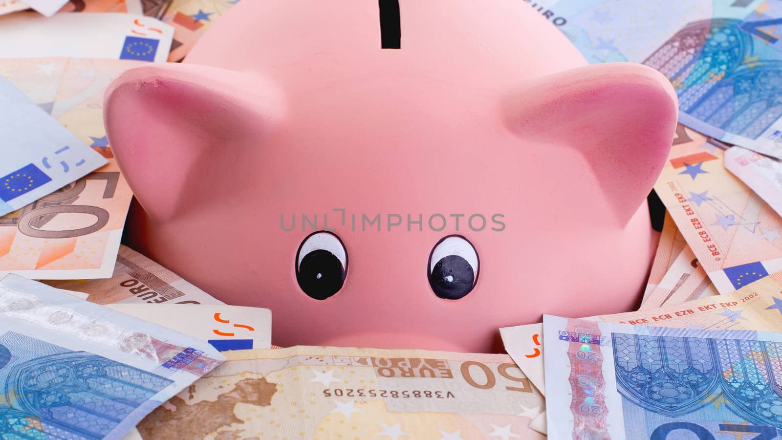 Unique pink ceramic piggy bank drowning in money, isolated on white