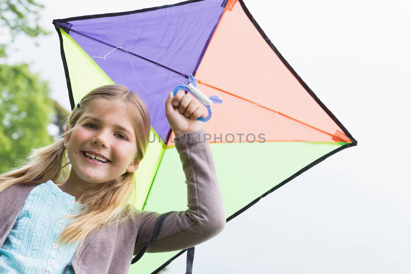 Portrait of a cute young girl with a kite standing outdoors