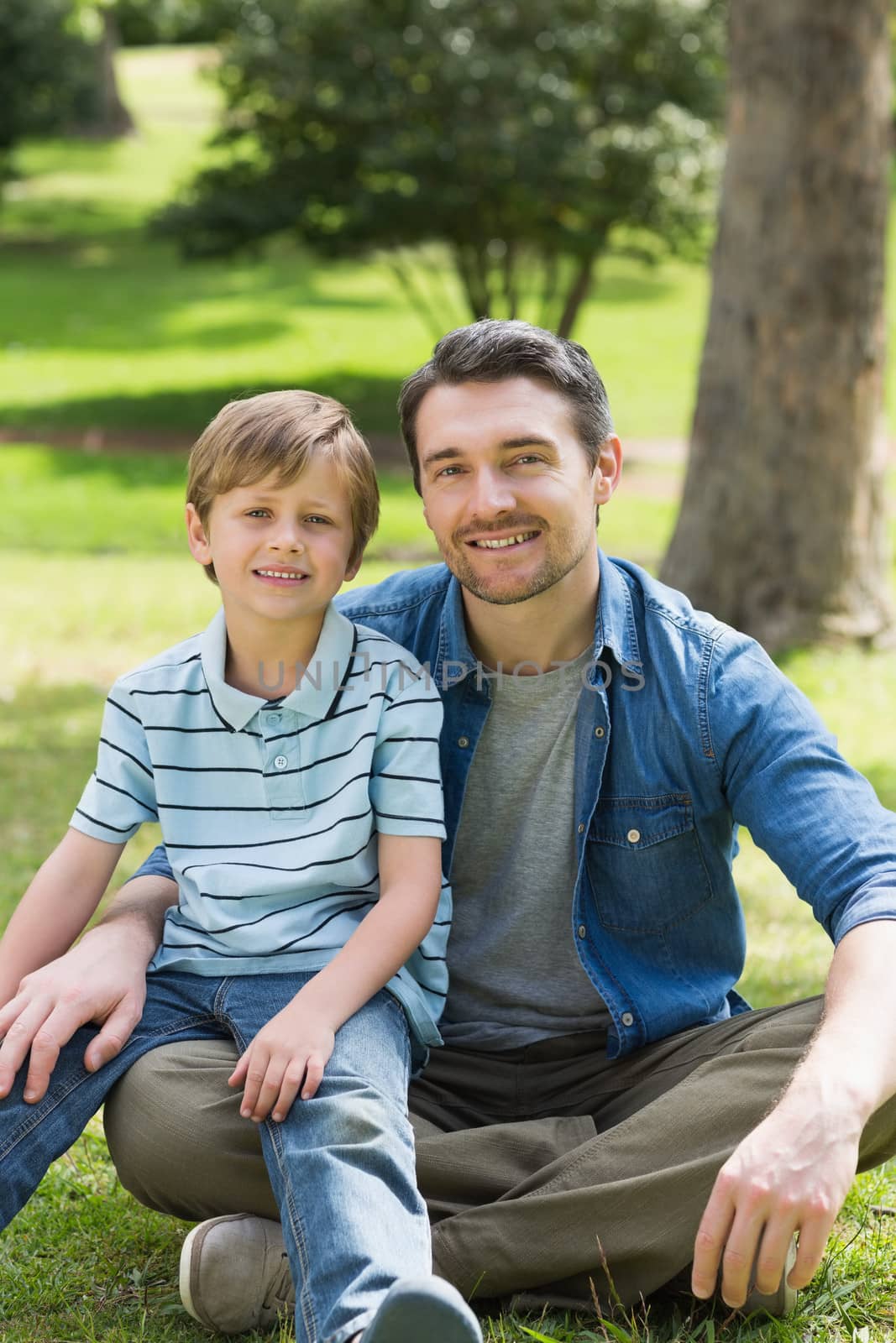 Portrait of a father and young boy sitting at the park