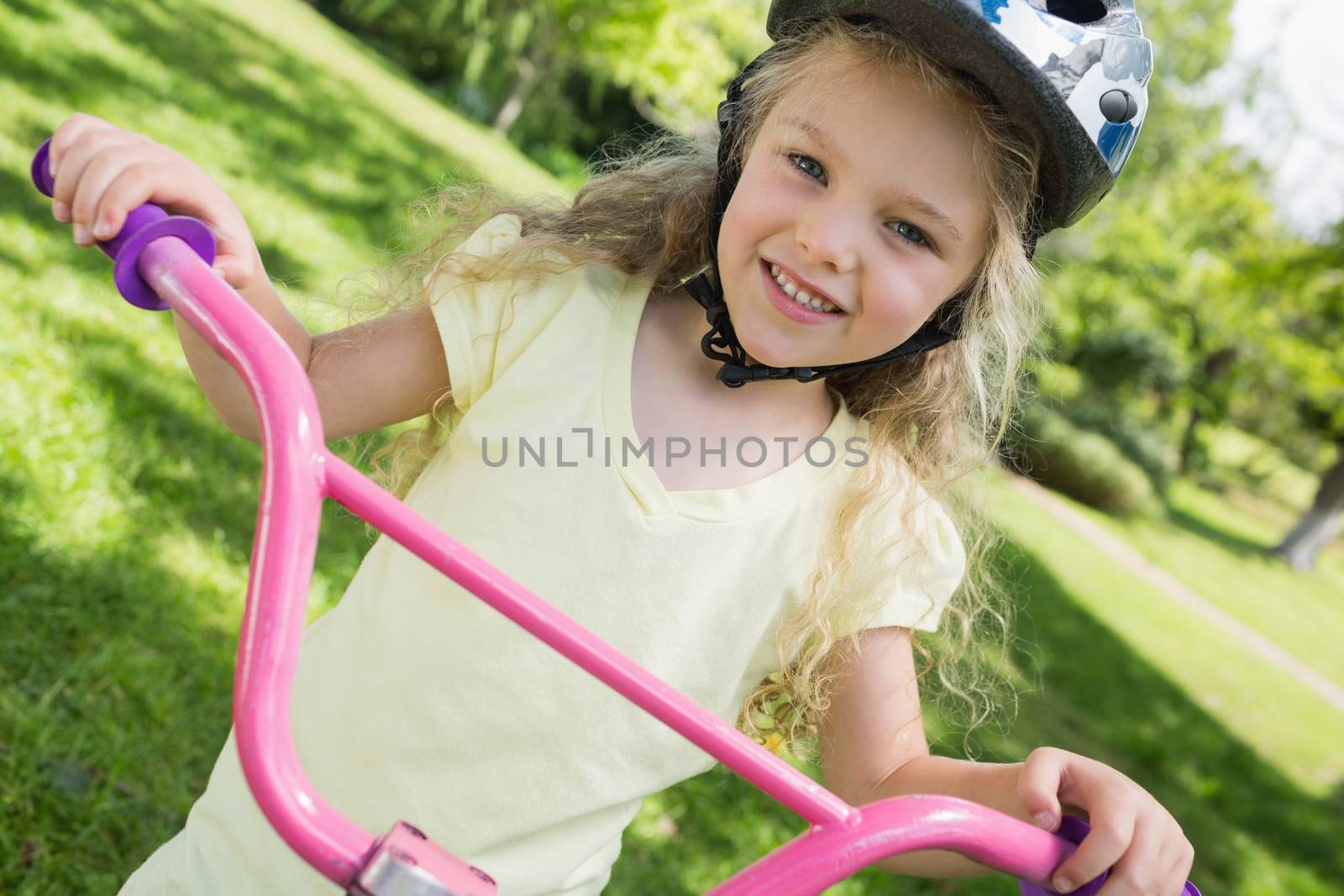 Close-up portrait of a little girl on a bicycle at summer park