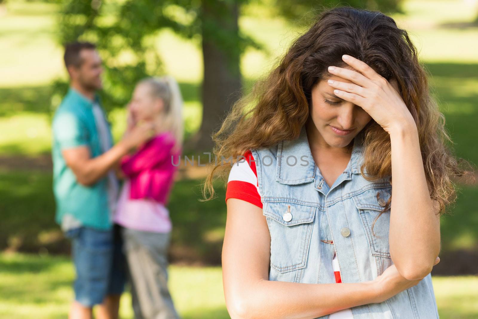 Angry woman with man and girlfriend in background at park by Wavebreakmedia