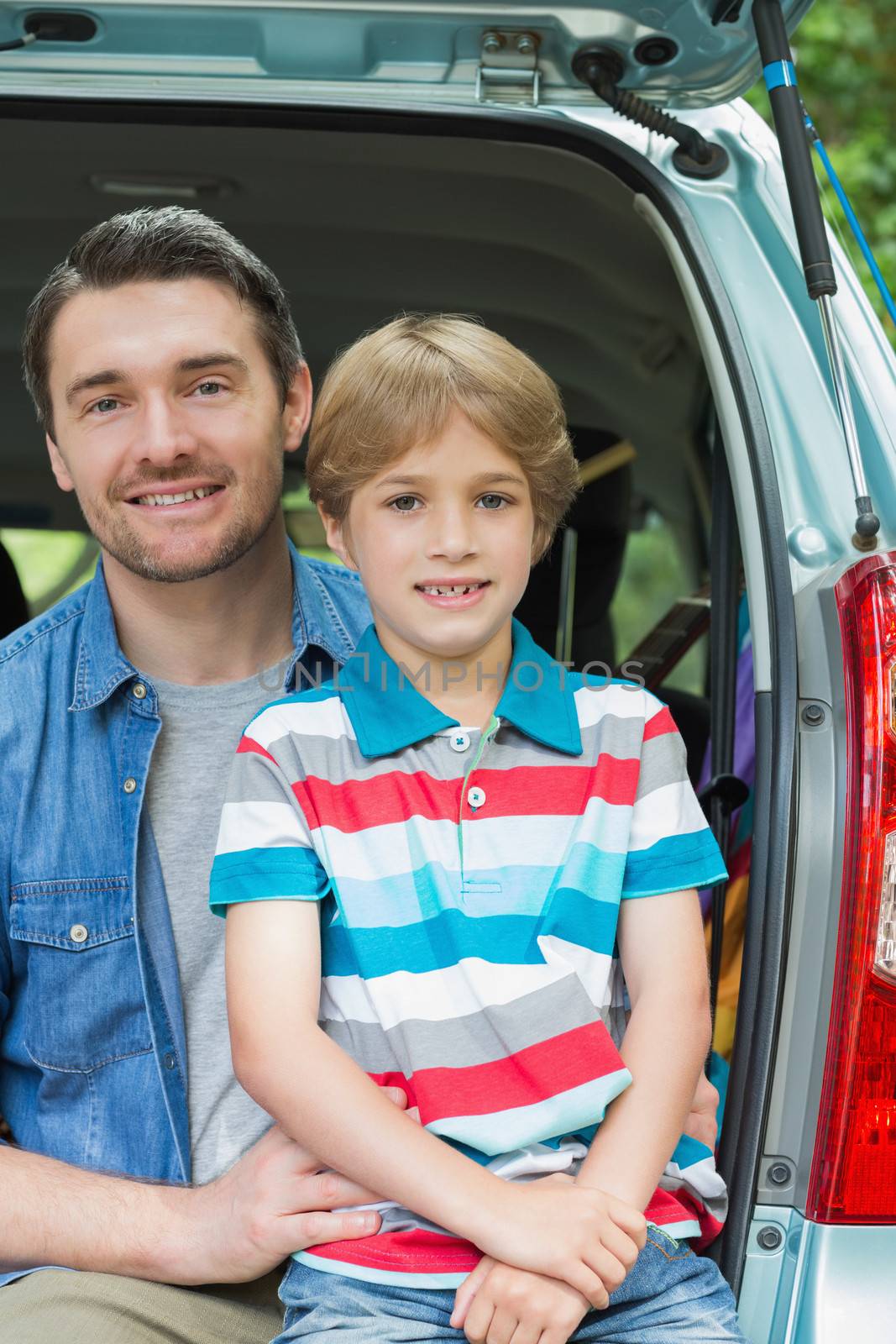 Happy father and son sitting in car trunk by Wavebreakmedia