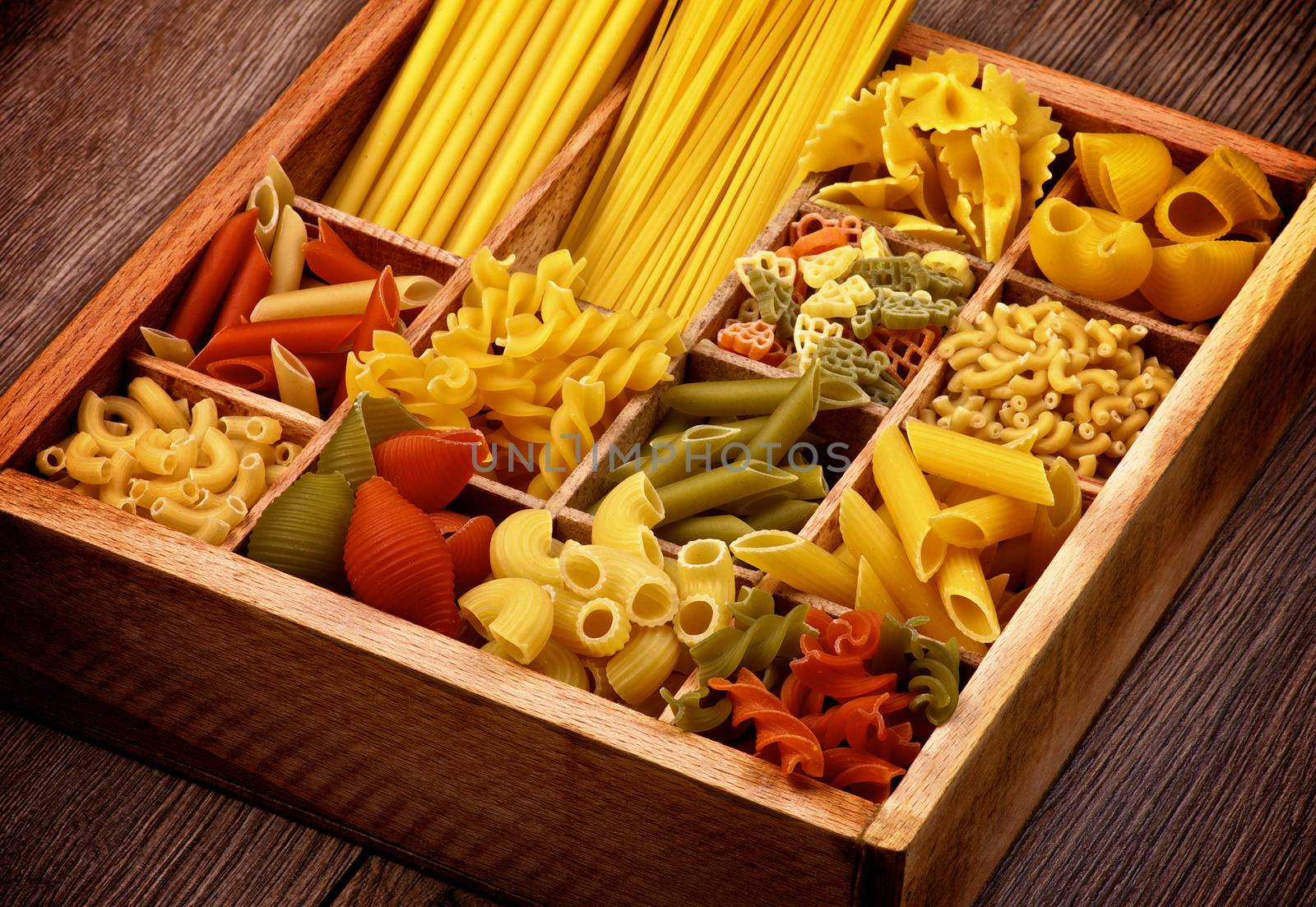 Various Raw Dry Pasta in Wooden Box Cross Section on Rustic Wooden background