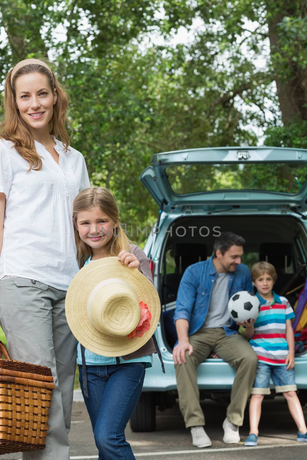 Portrait of mother and daughter with father and son sitting in car trunk