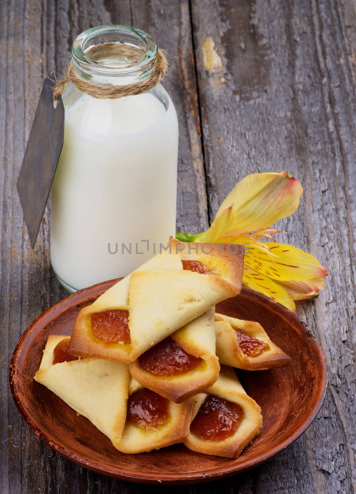 Homemade Pastry Jam Wrapped and Bottle of Milk Decorated with Yellow Flower isolated on Rustic Wooden background