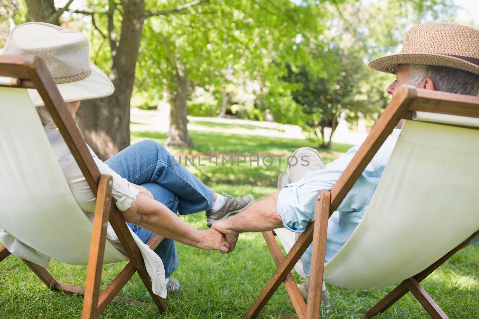 Mature couple sitting in deck chairs at park by Wavebreakmedia