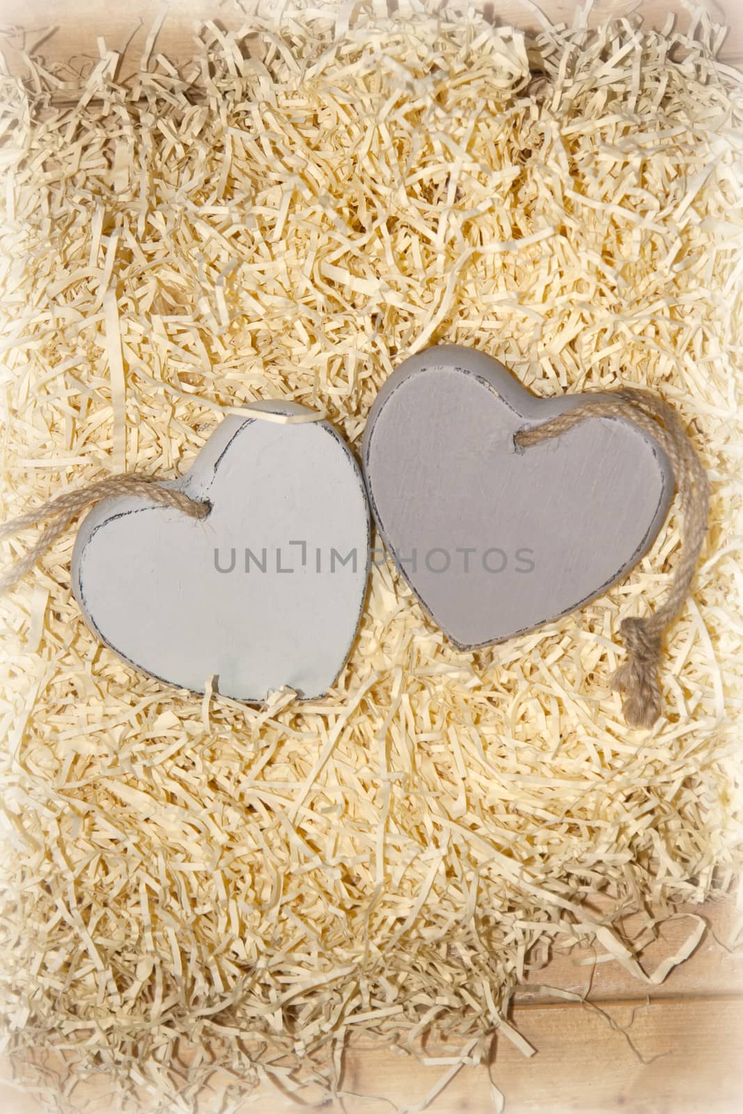 two wooden hearts in a love nest made of straw on a wooden background