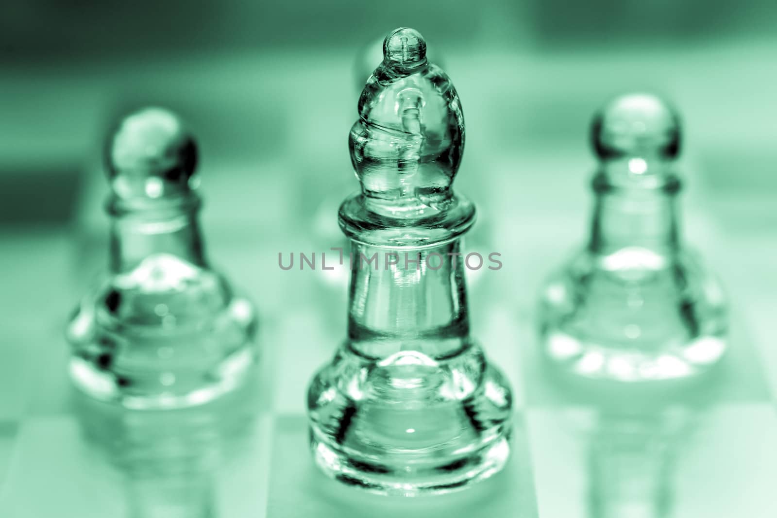 Bishop chess piece with pawns in the background pieces made out of glass