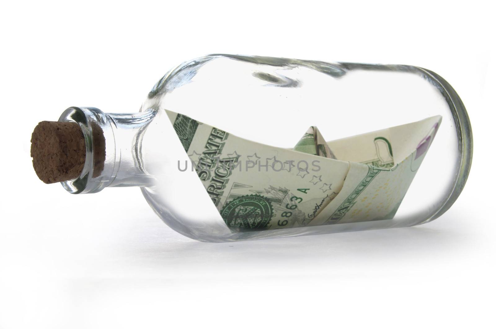 Paper boat made from dollar banknotes inside a message bottle 