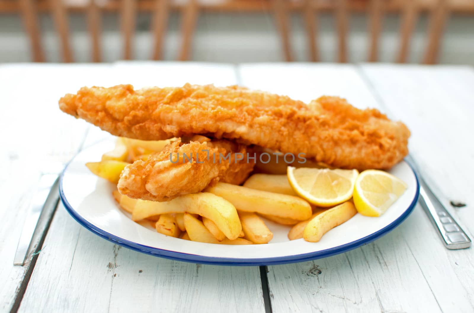 Two pieces of battered fish on a plate with chips 