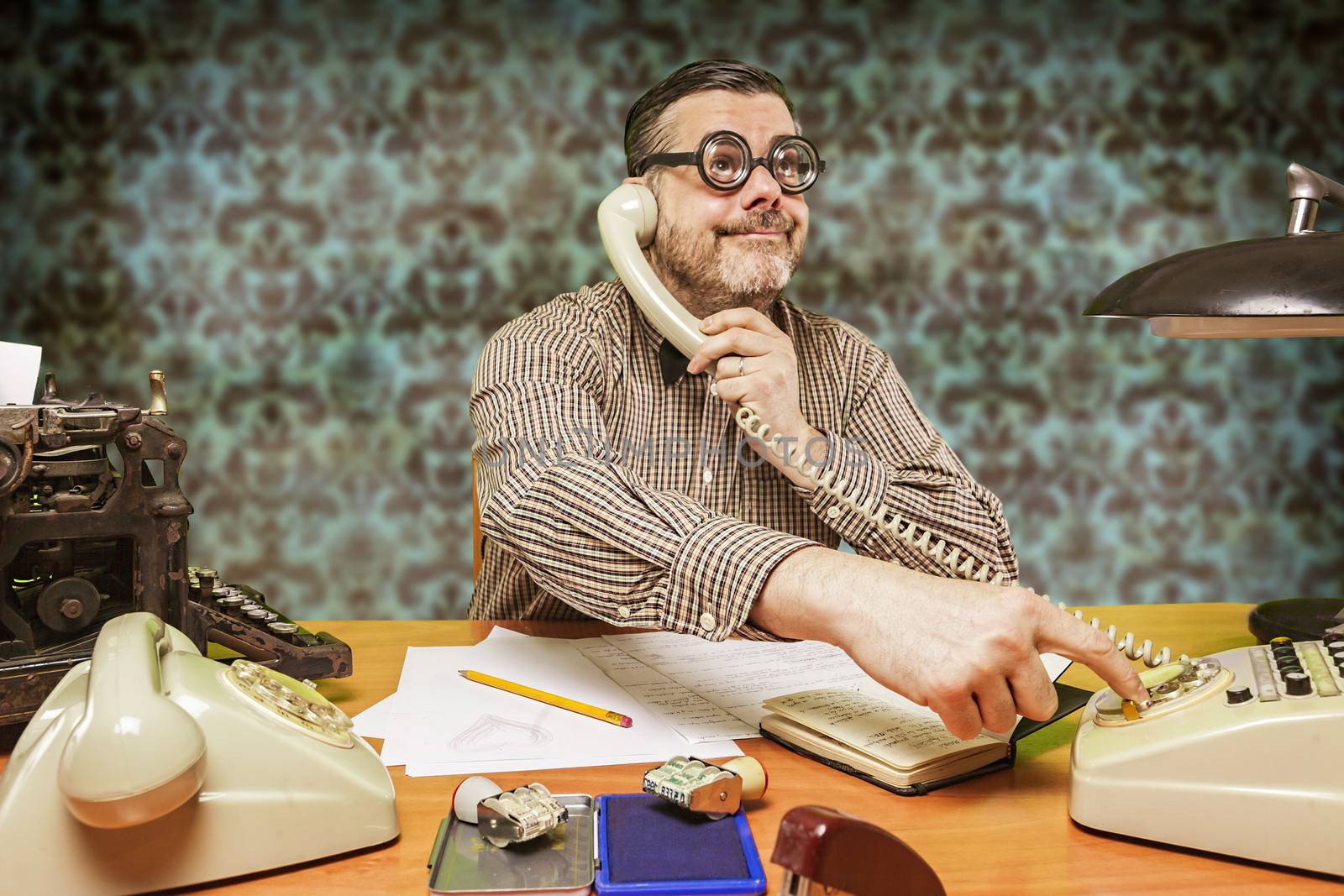 Employee with glasses talking on the phone in the office in the 1960s