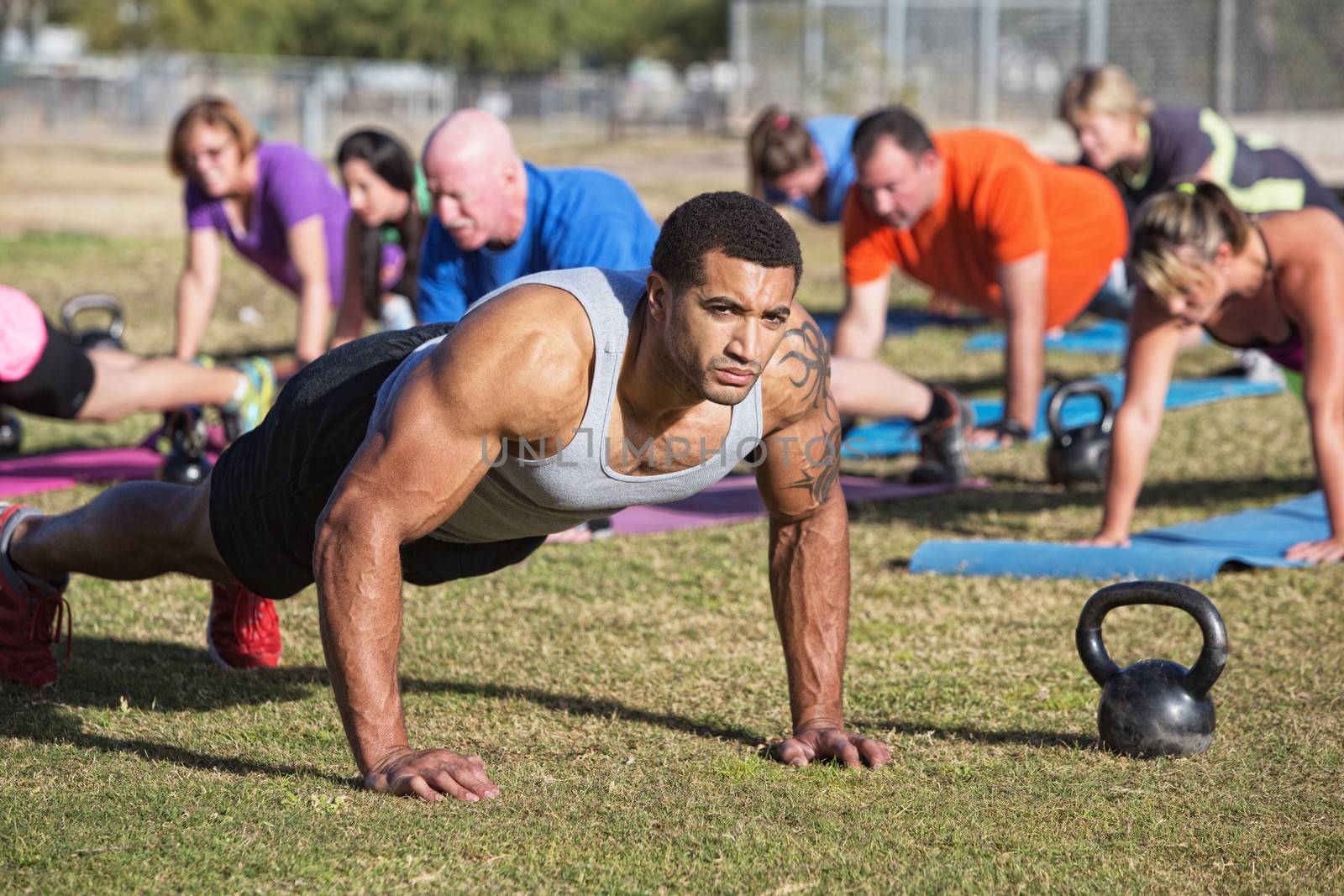Group of serious adults doing push-ups outdoors