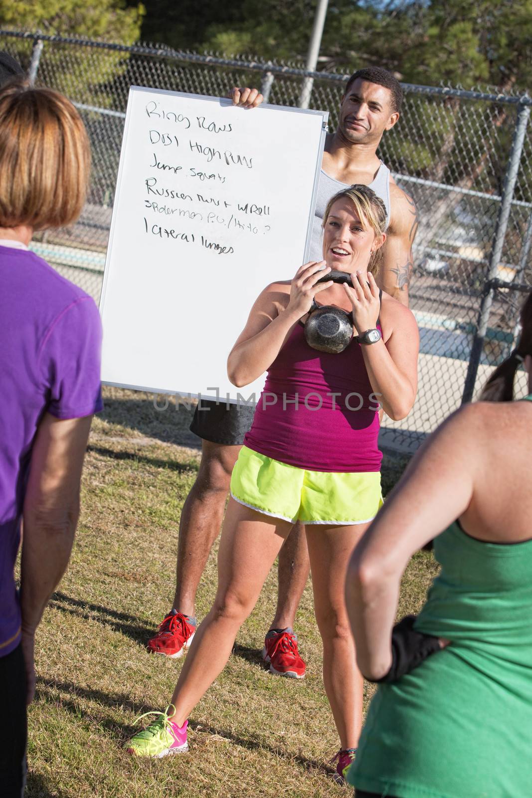 Boot camp fitness instructors explaining how to lift weights