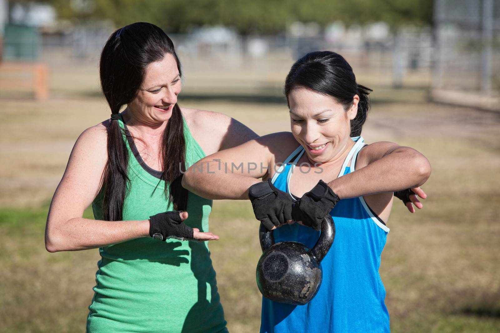 Friendly fitness instructor helping student use kettle bell weight