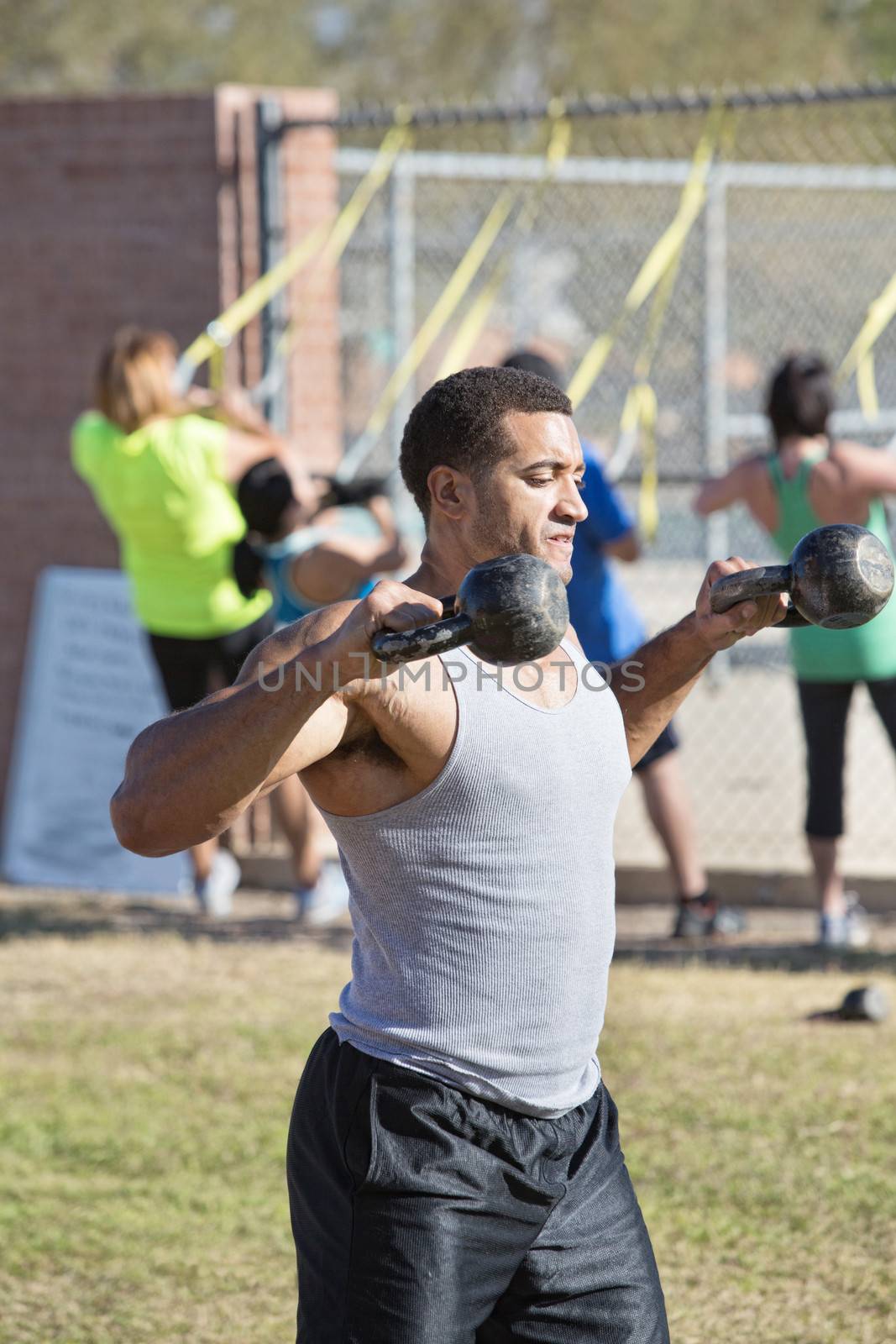 Strong young man exercising shoulders with kettle bell weights