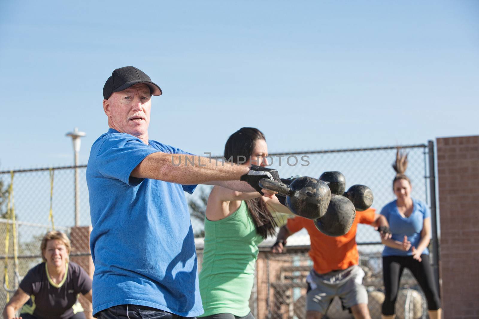 Mature male lifting kettle bell weights in outdoor class