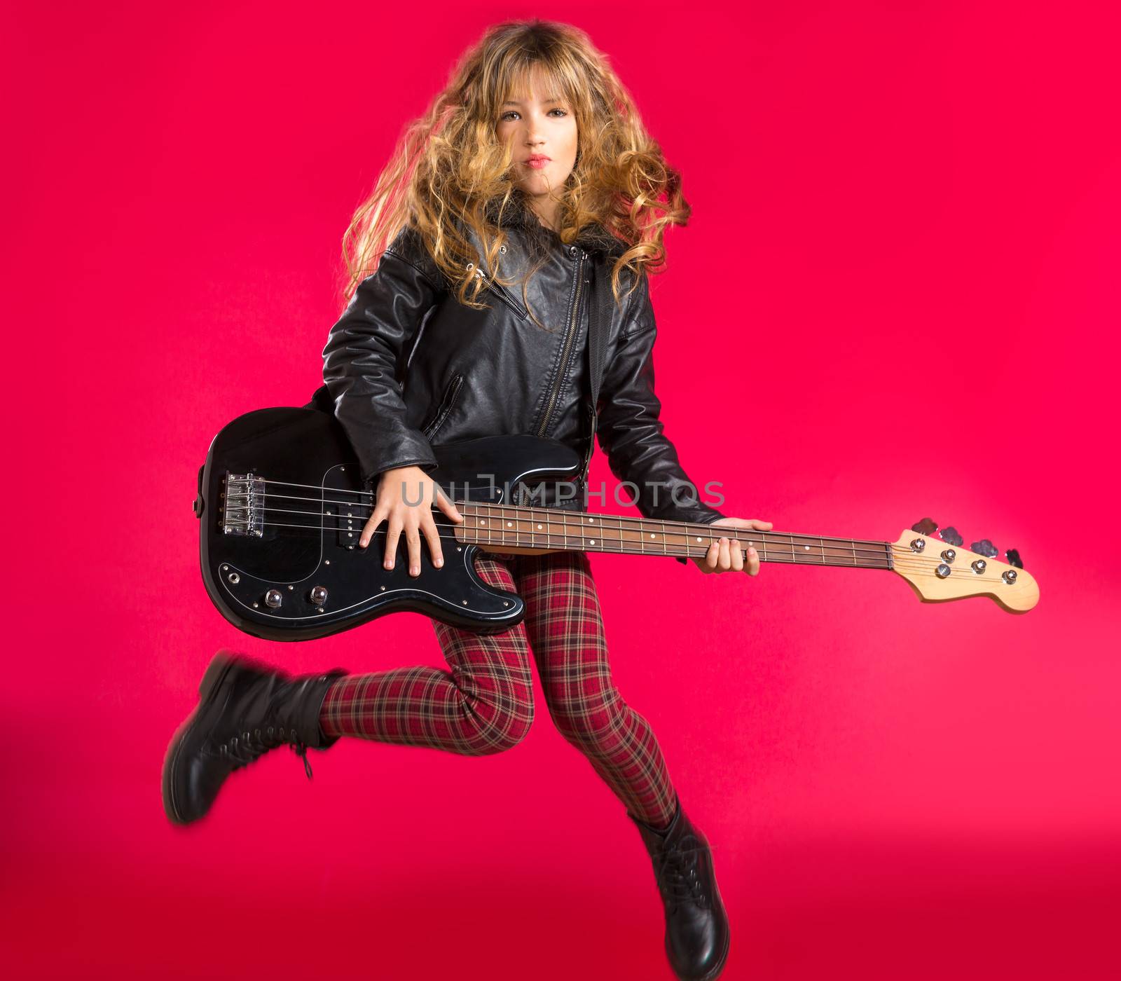 Blond Rock and roll girl jumping playing bass guitar on red background