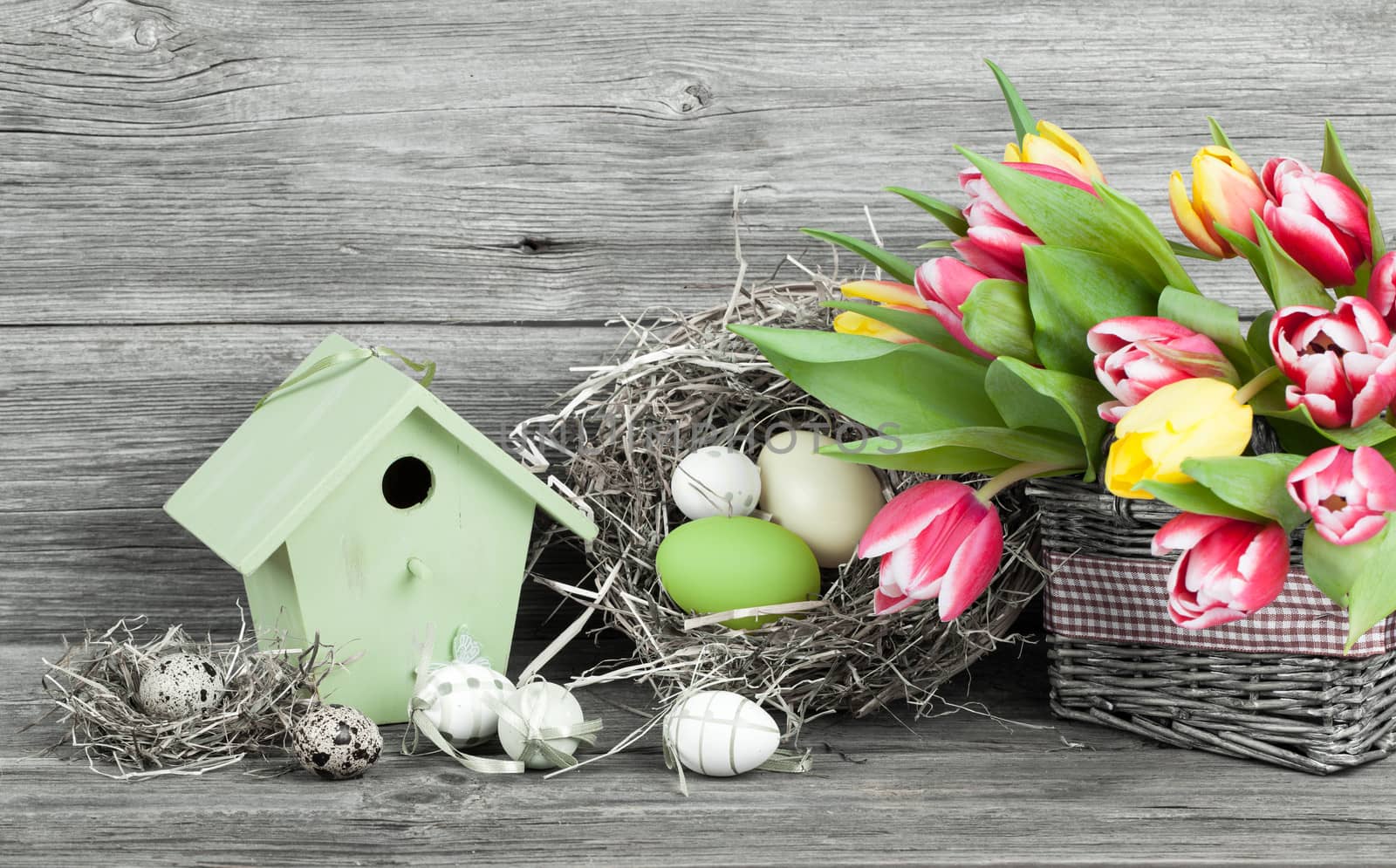 easter decoration with eggs, birdhouse and tulips. wooden background
