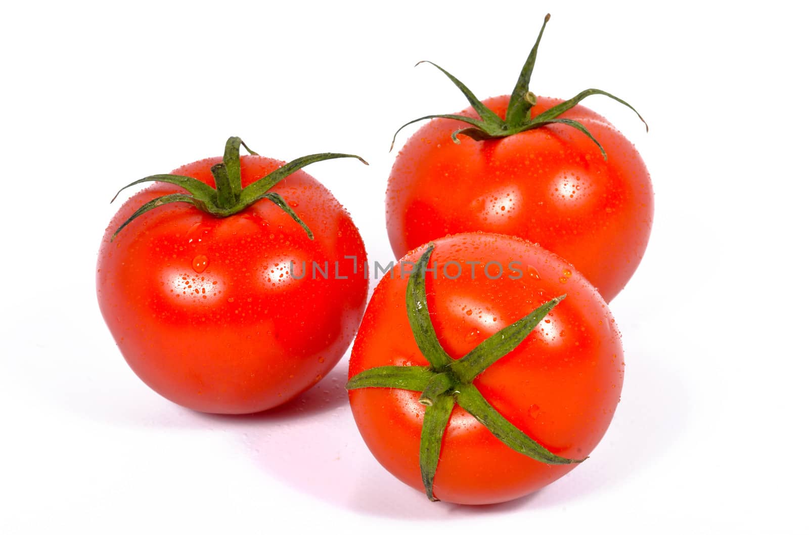 three fresh tomatoes with green leaves isolated on white background