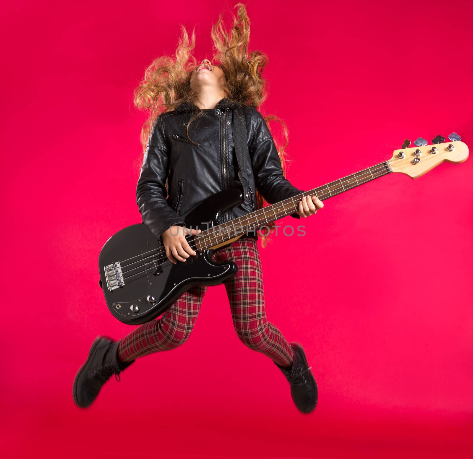 Blond Rock and roll girl jumping playing bass guitar on red background