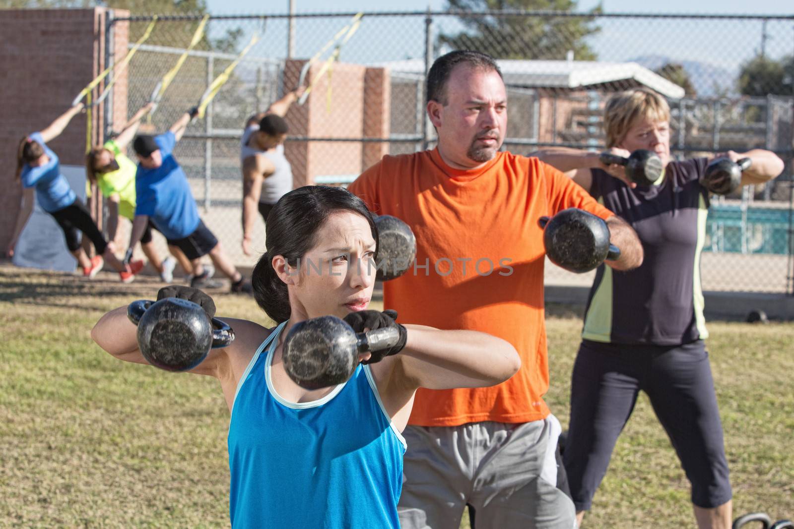 Men and women in boot camp fitness class outdoors