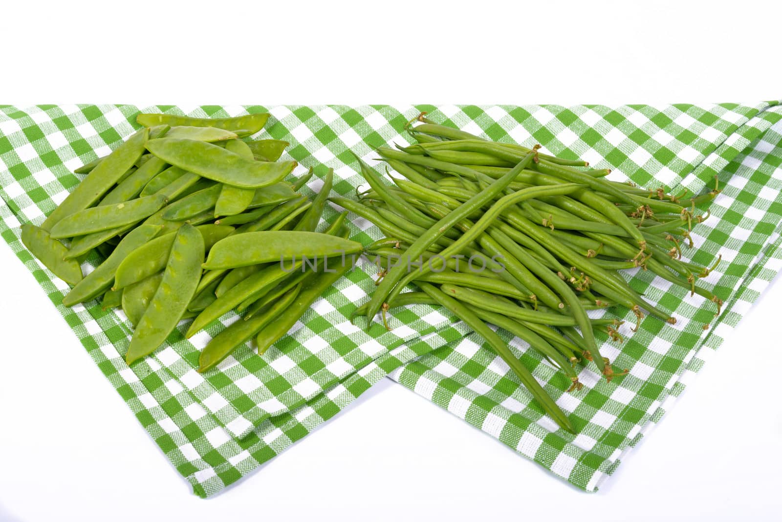 green beans and peas on a green towel by philipimage