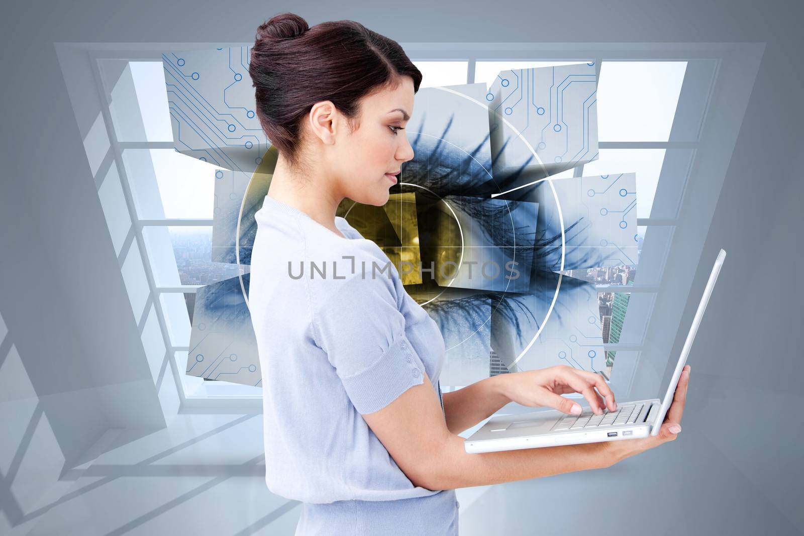 Confident businesswoman using a laptop against room with large window showing city