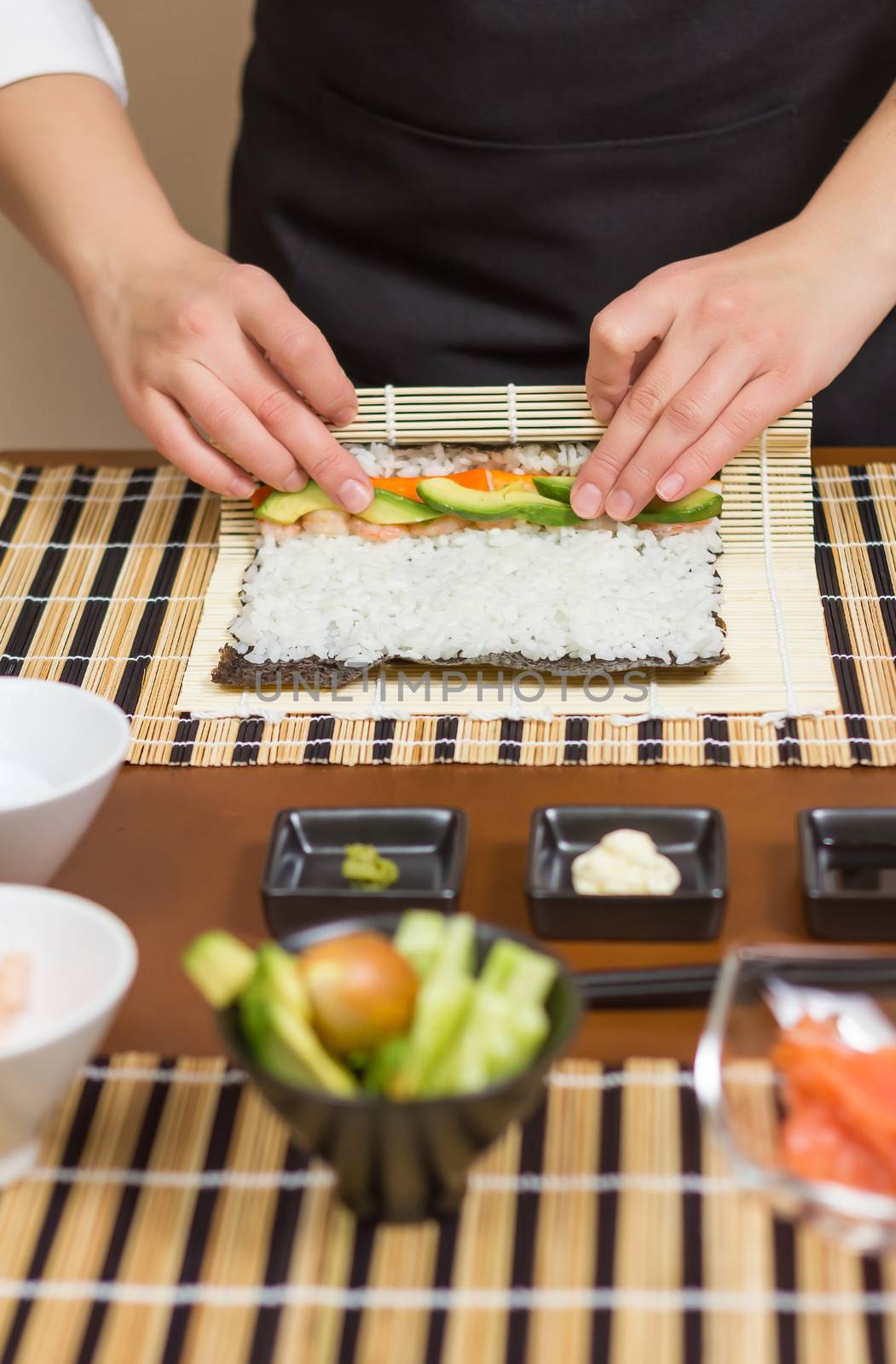 Hands of woman chef rolling up a japanese sushi by doble.d
