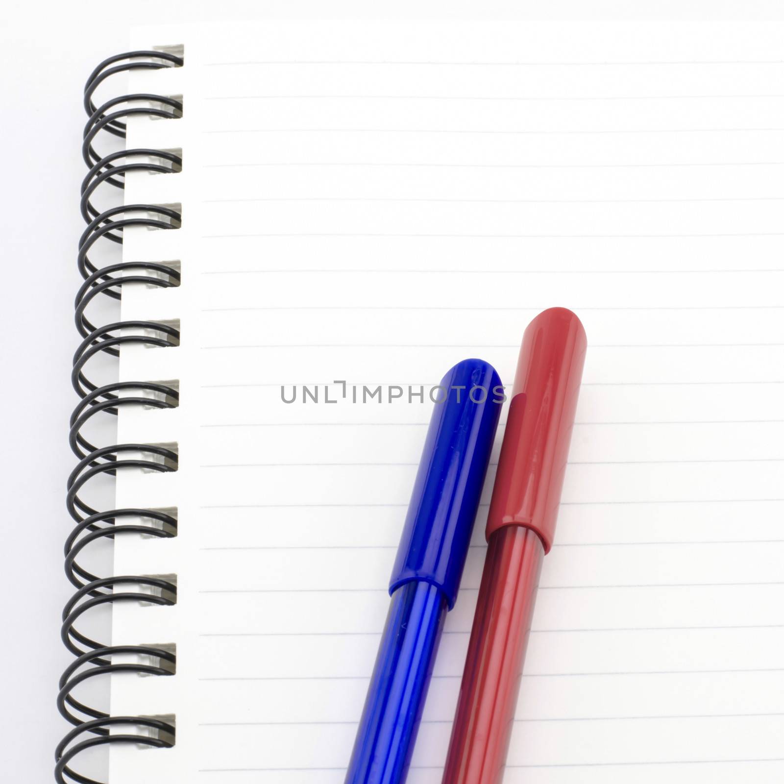 blue and red pen with notebook isolated on white by ammza12