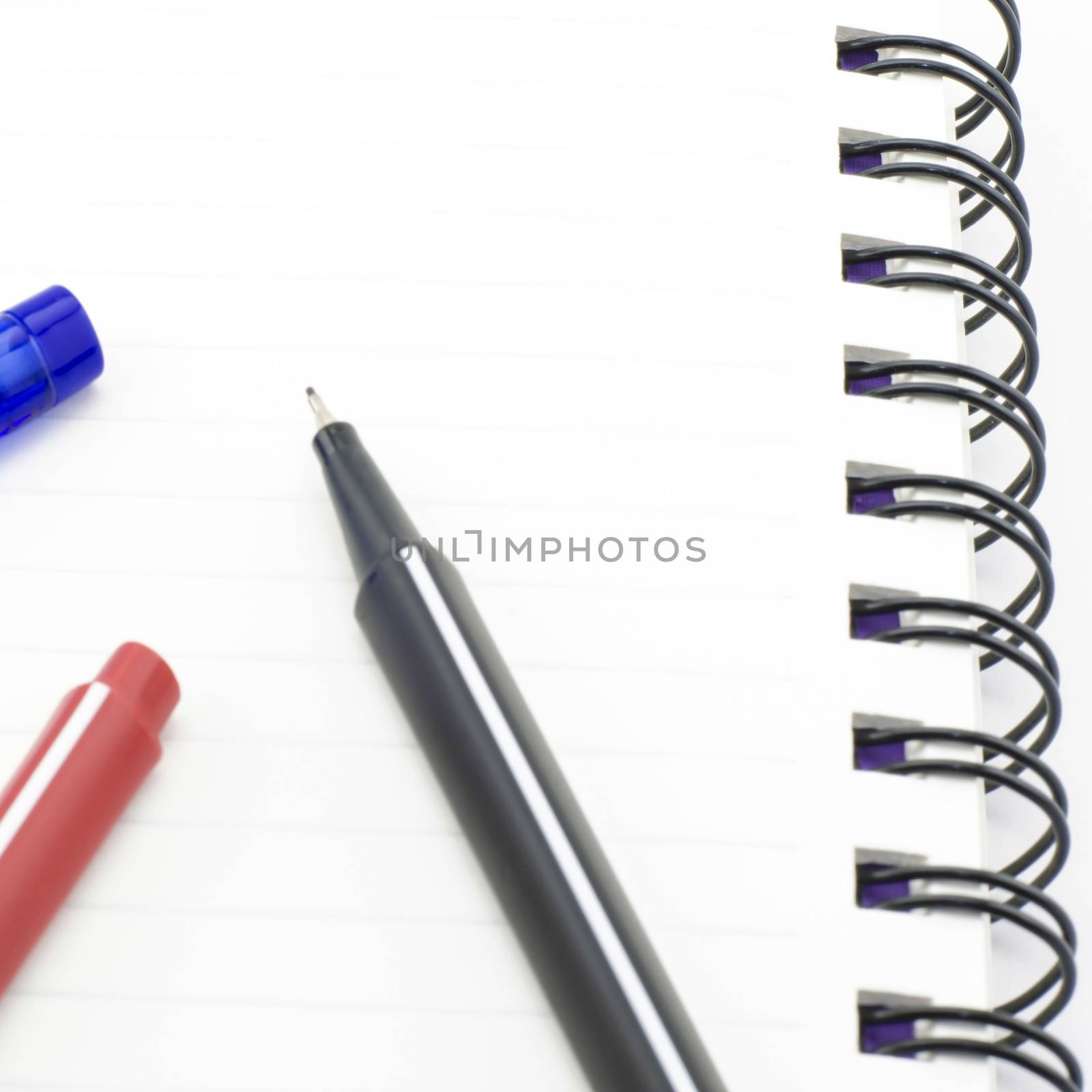black red and blue pen with notebook isolated on white by ammza12