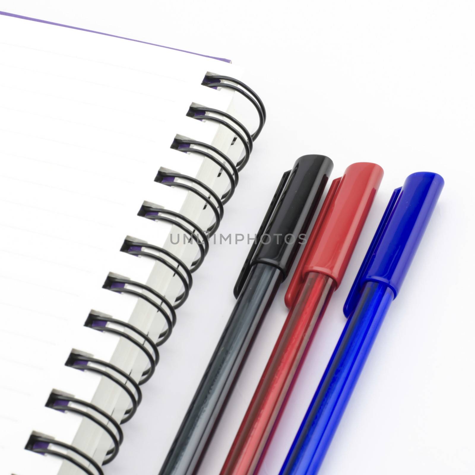 black red and blue pen with notebook isolated on white background