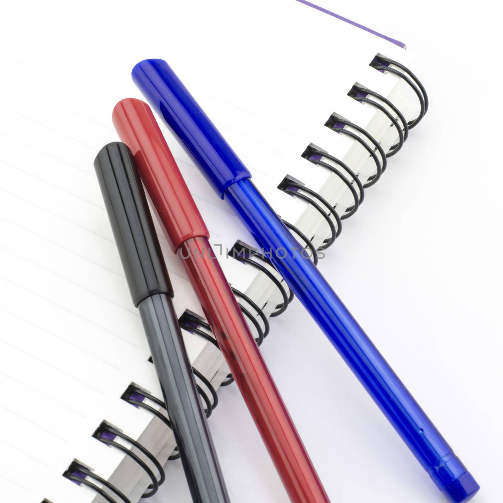 black red and blue pen with notebook isolated on white background