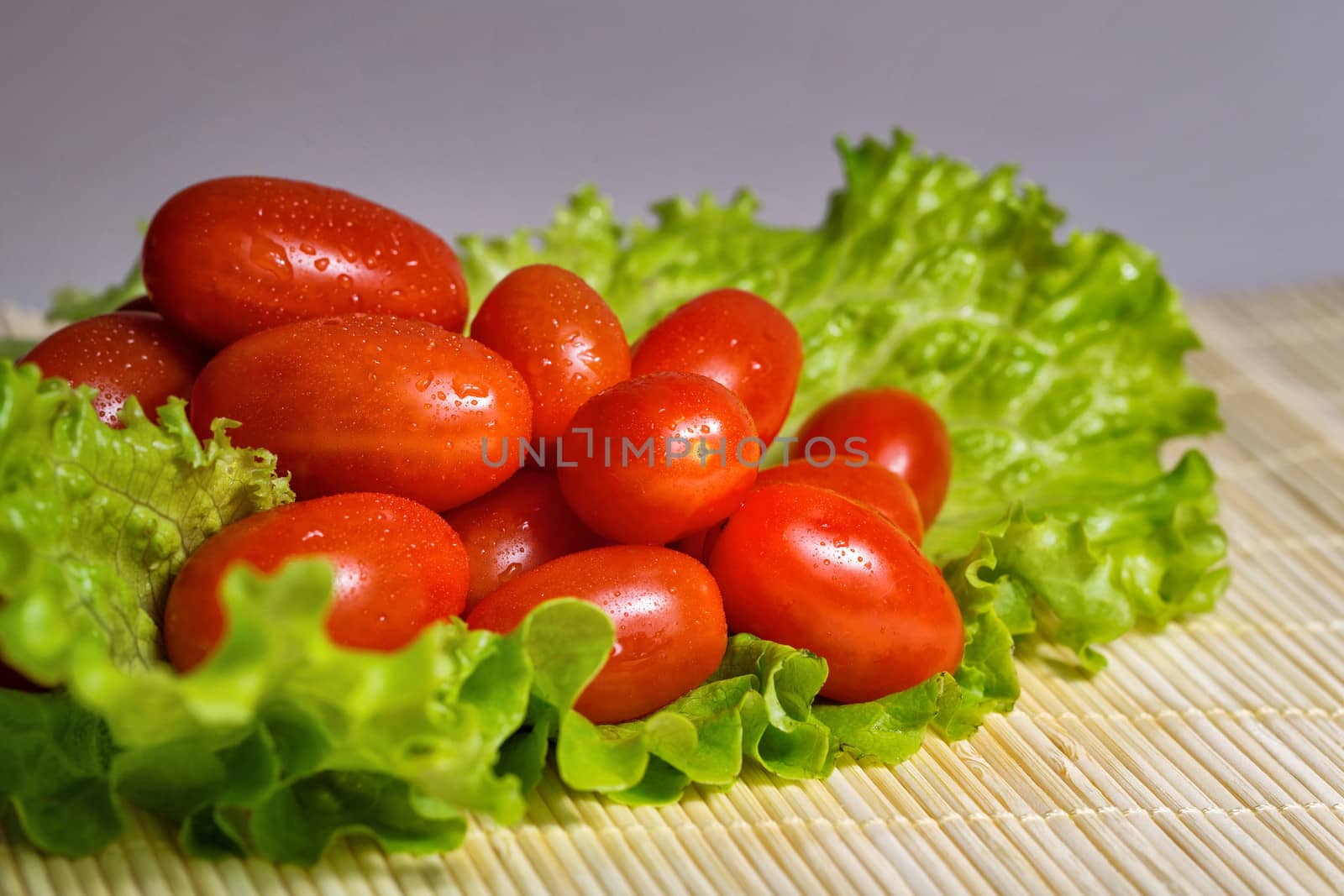 Vegetarian tomato and lettuce on bamboo tray are photographed close-up