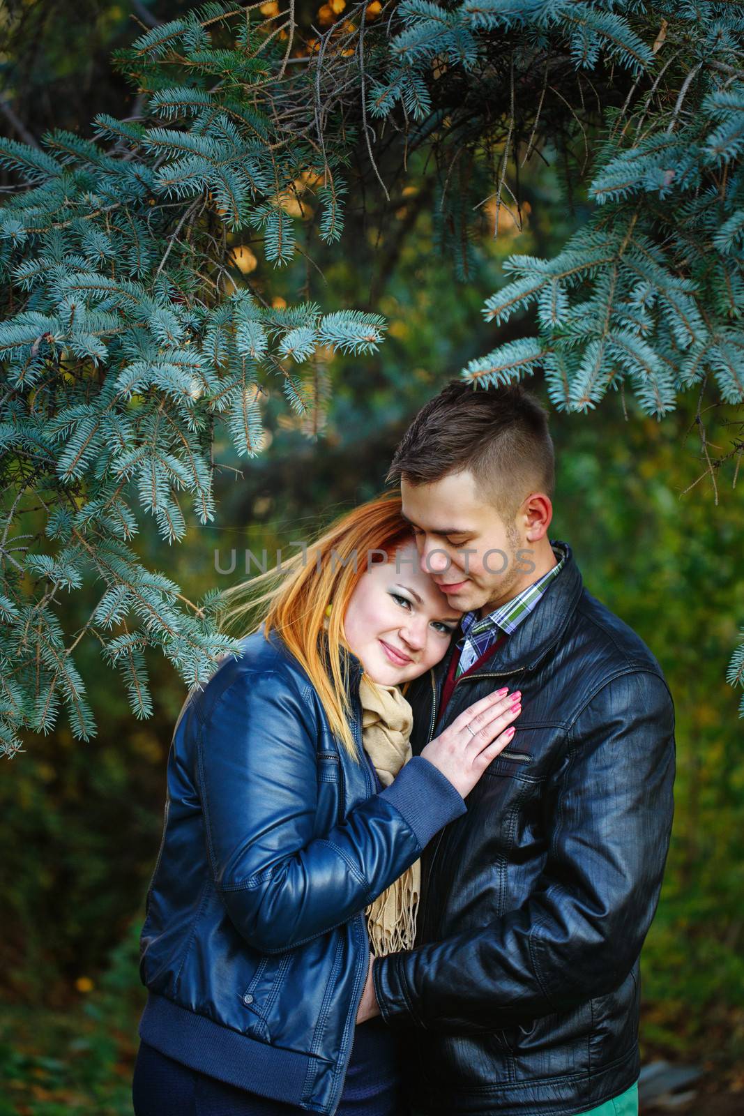 Attractive young couple embracing in a city park on a background of fir trees