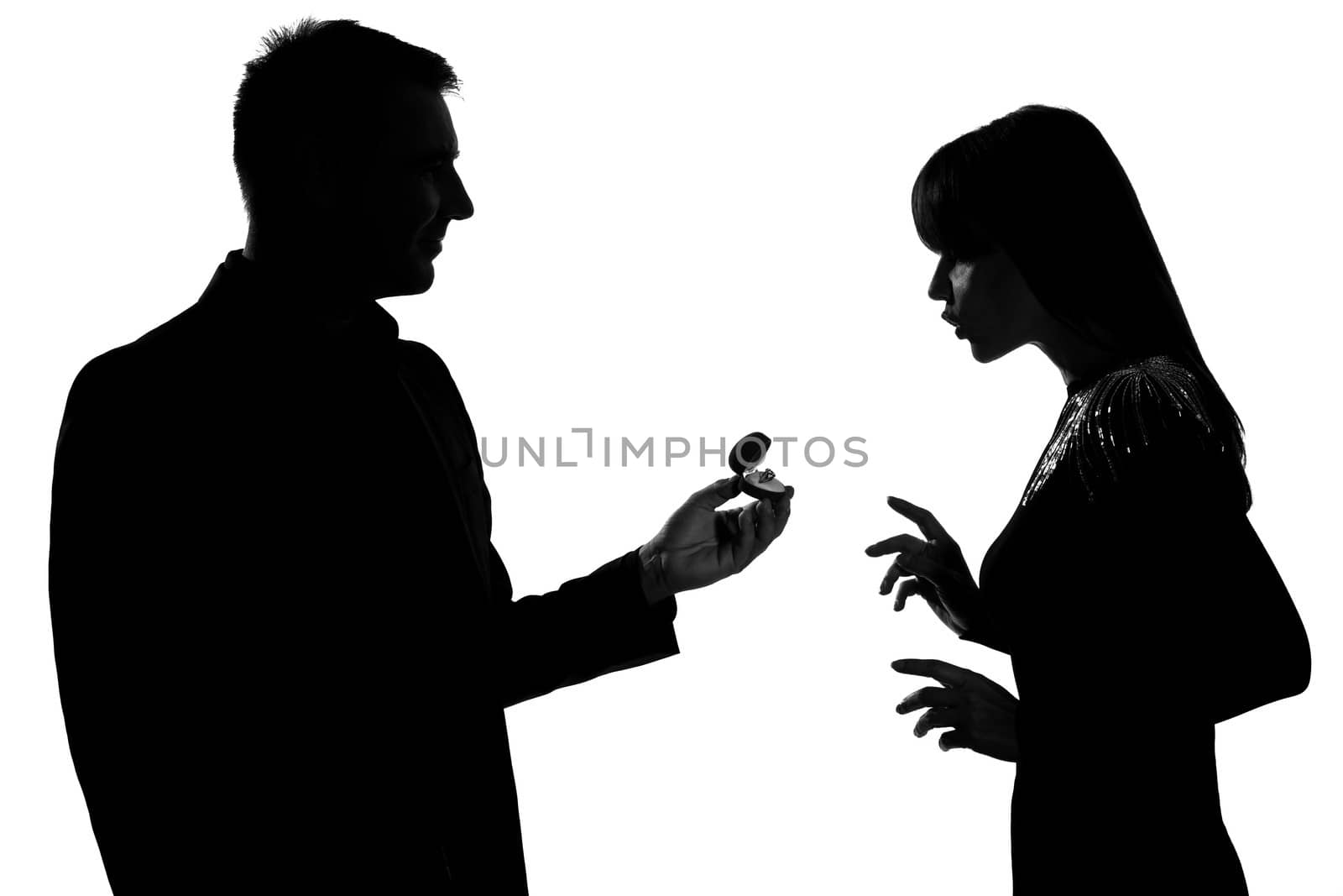 one caucasian couple man offering engagement ring and woman surprised in studio silhouette isolated on white background