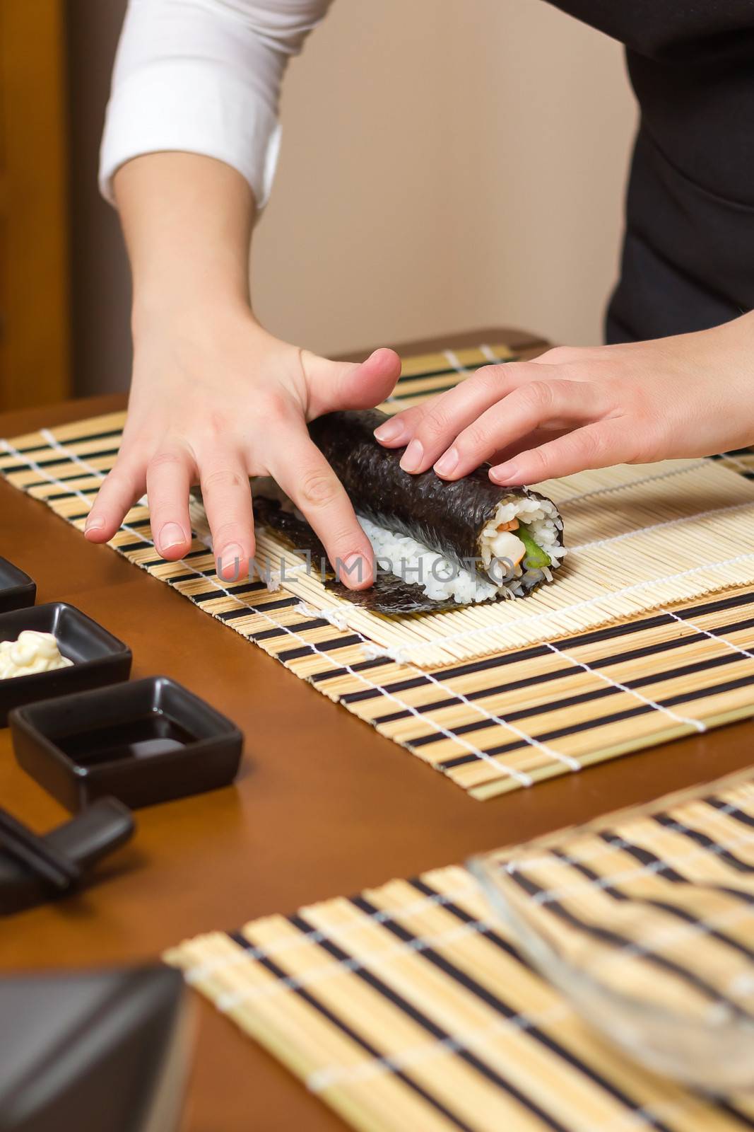 Woman hand moistening with water a sushi roll edge by doble.d
