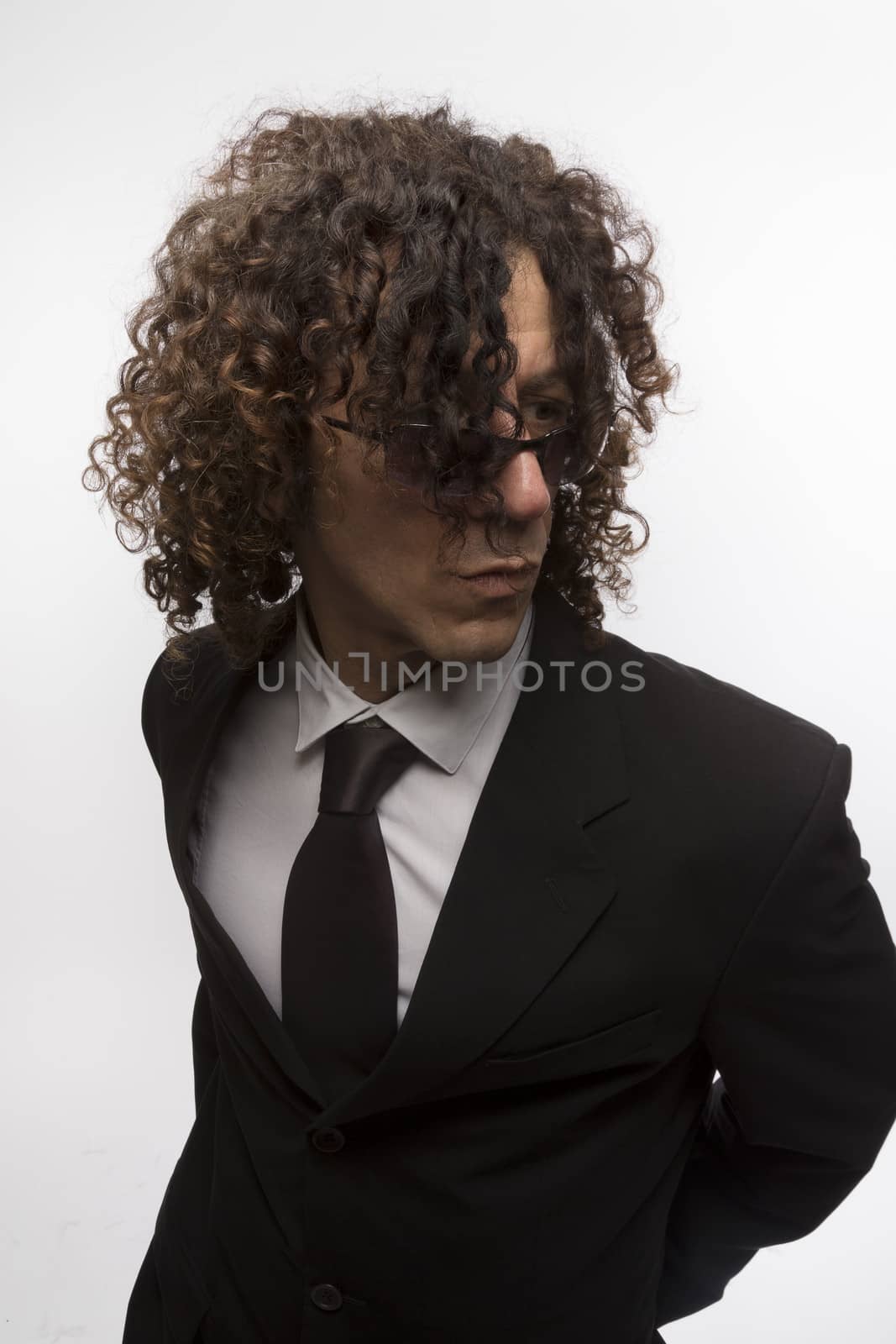 Cropped portrait of mediterranean looking man with curly hair wearing business suit and sun glasses