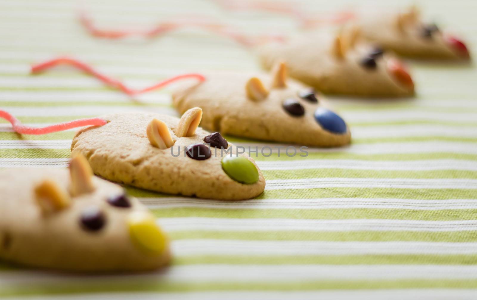 Cookies with mouse shaped and red licorice tail over green striped tablecloth