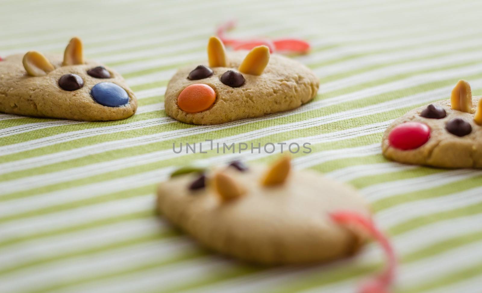 Cookies with mouse shaped and red licorice tail over green striped tablecloth