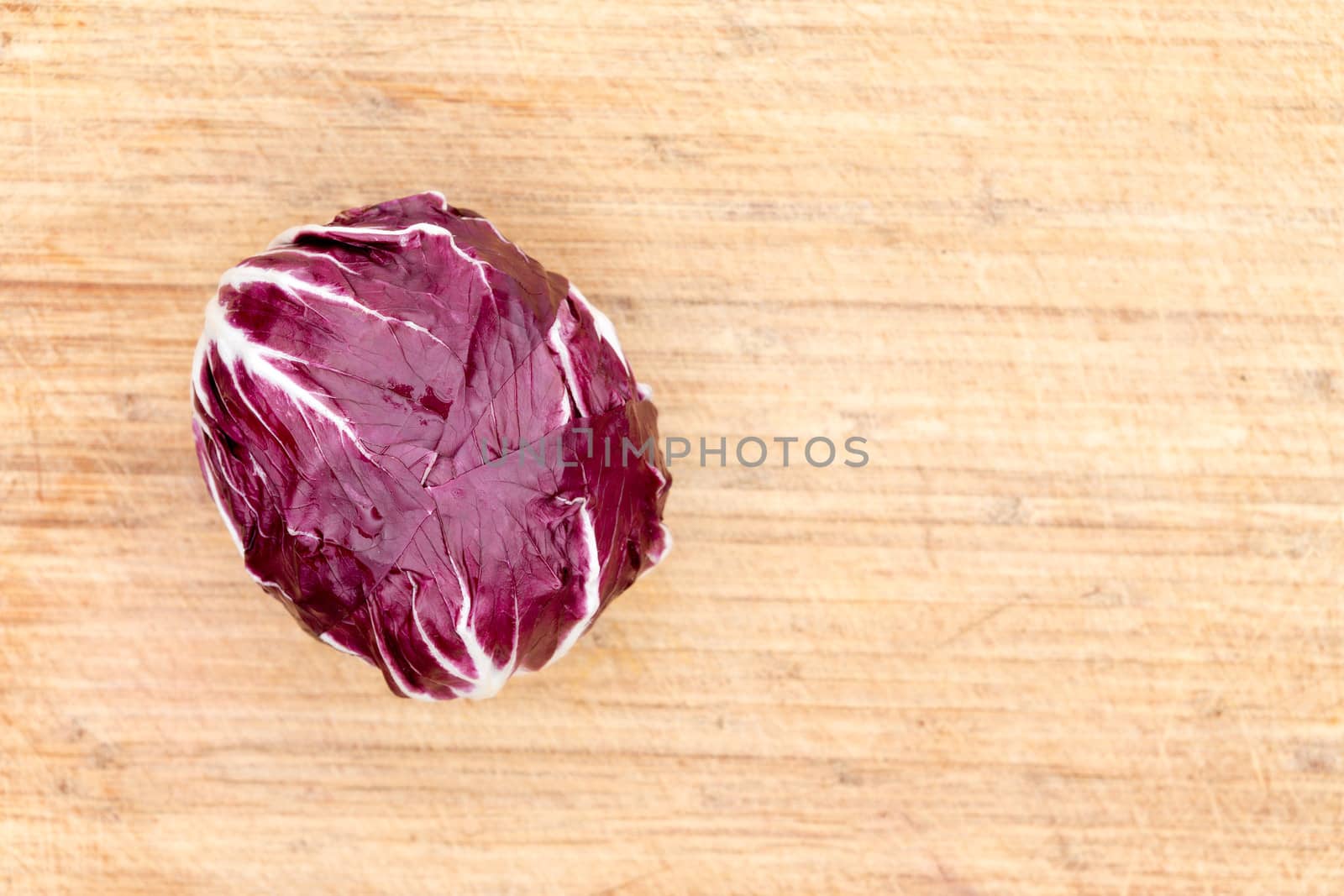 Overhead view of a single red radicchio rich in anthocyanin on a bamboo cutting board with copyspace