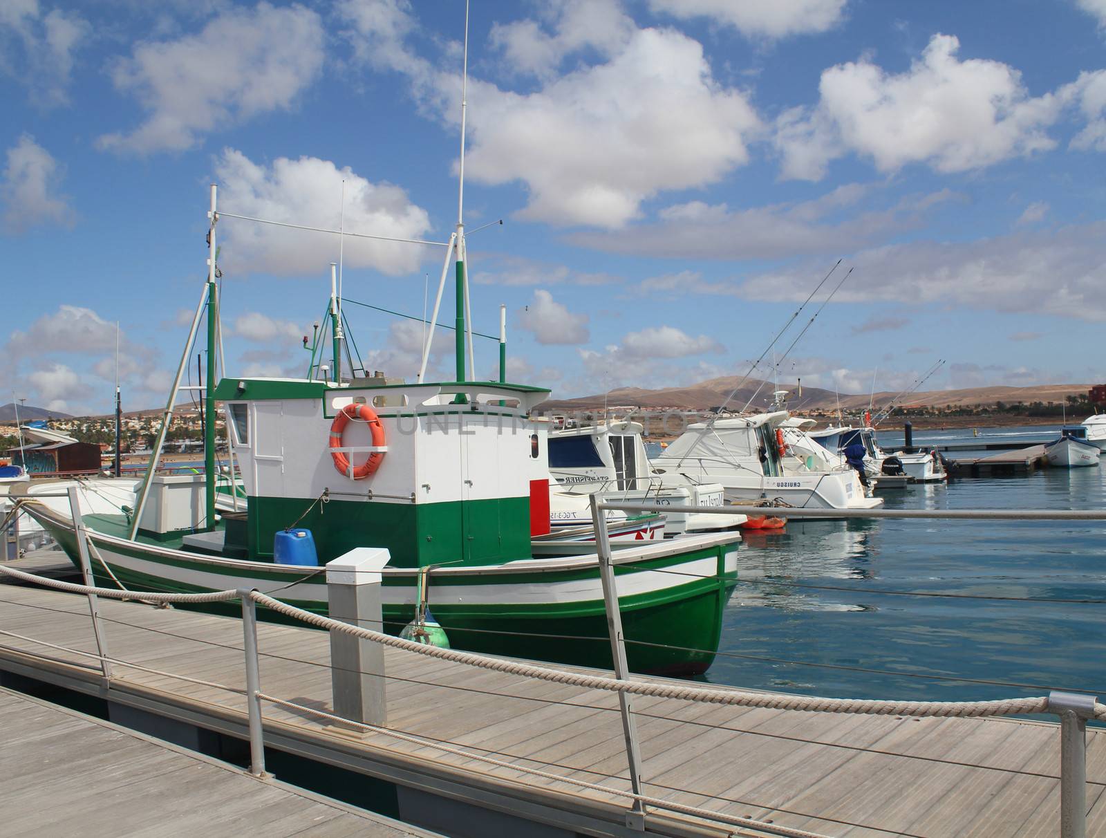 Many motor boats and masts in a marina with calm blue sea