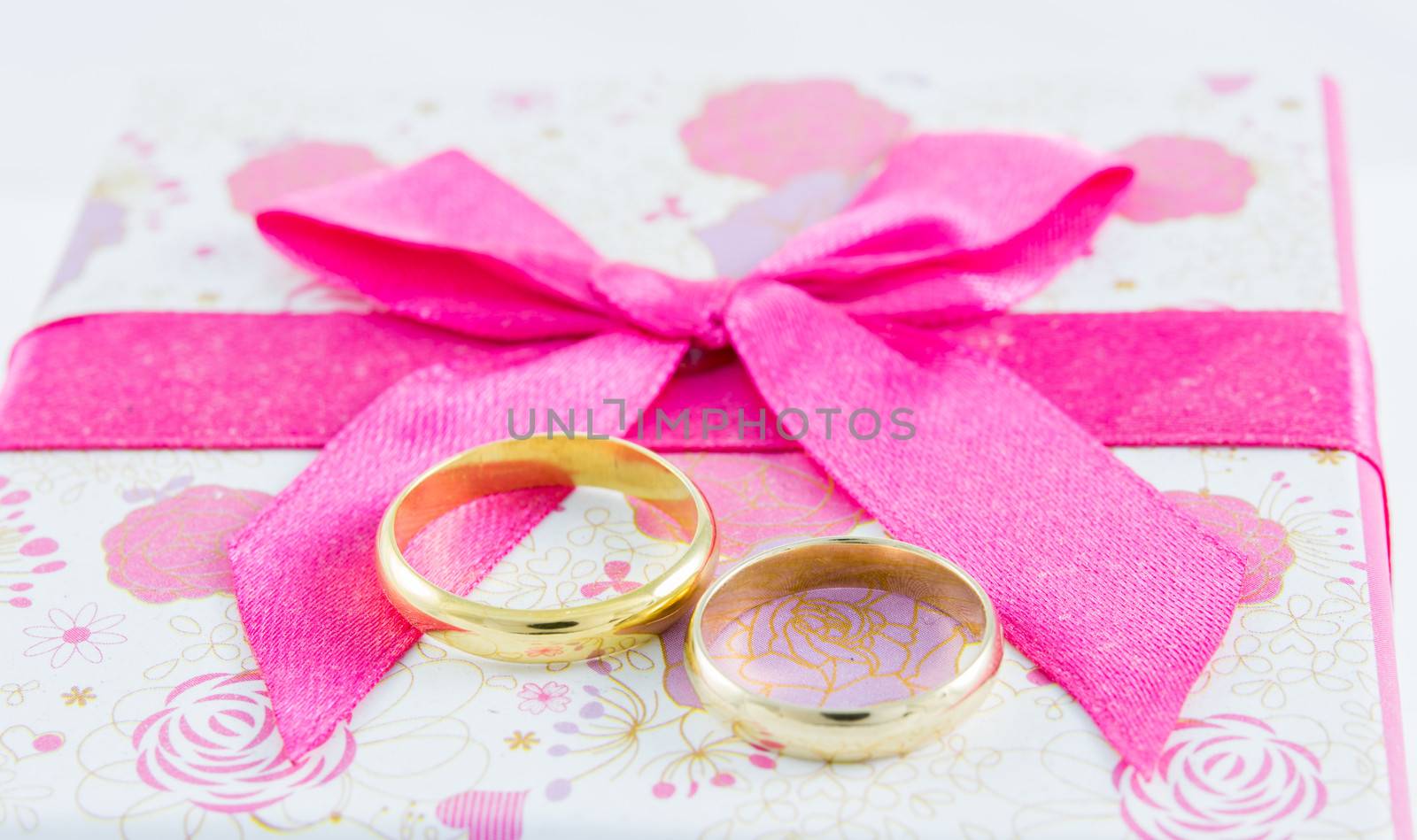 Wedding rings on gift box on white background