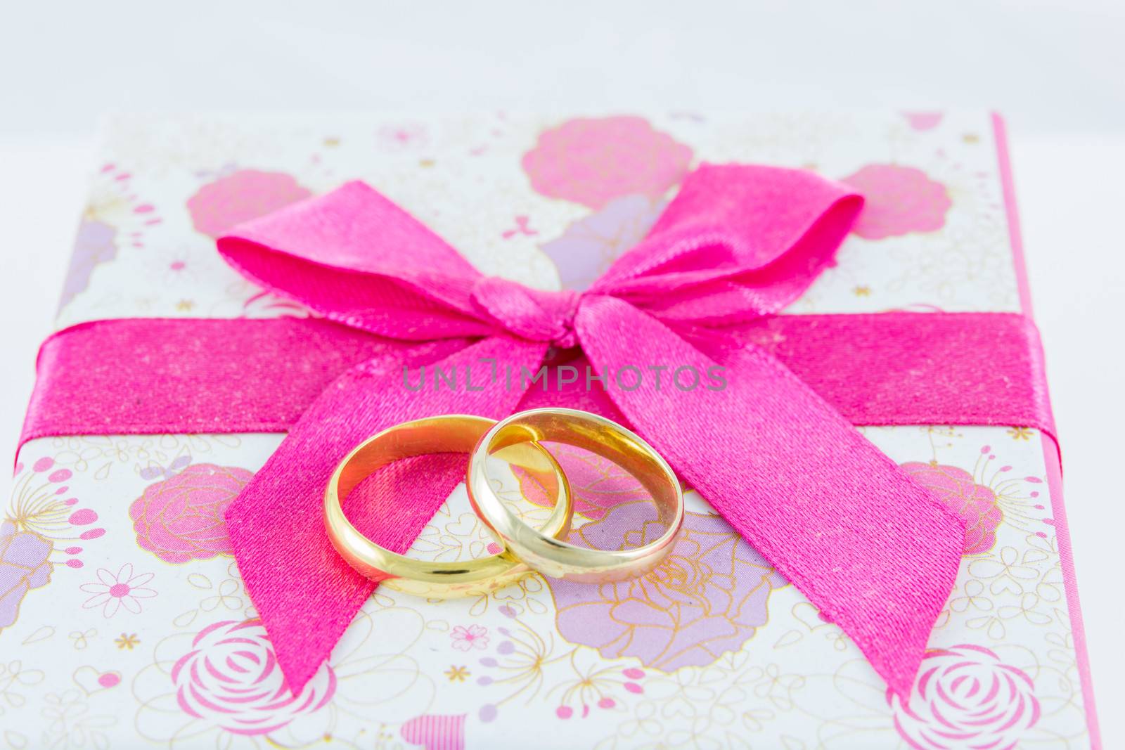 Wedding rings on gift box on white background