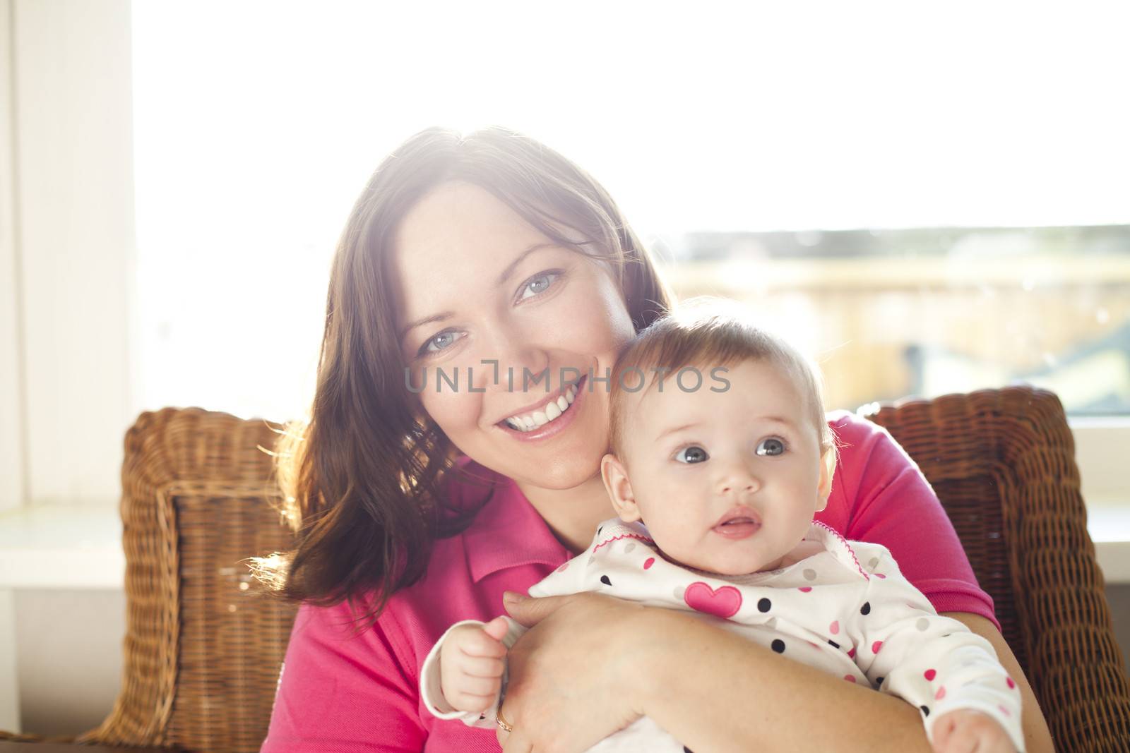 Mother with her infant is sitting at home in a sunny day