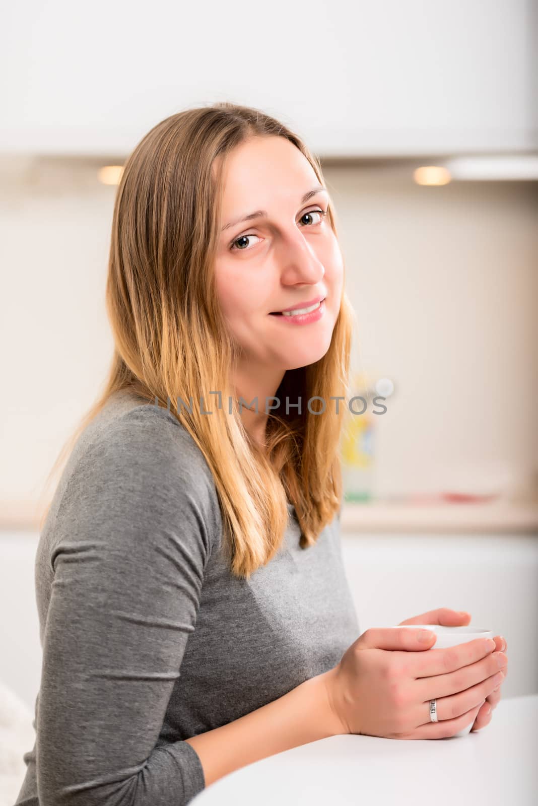 Happy girl in grey holding mug and looking at camera with smile