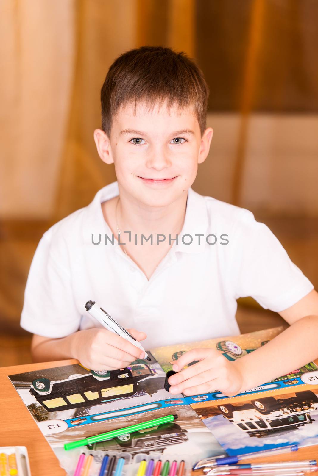 Boy colouring book looking at camera smiling