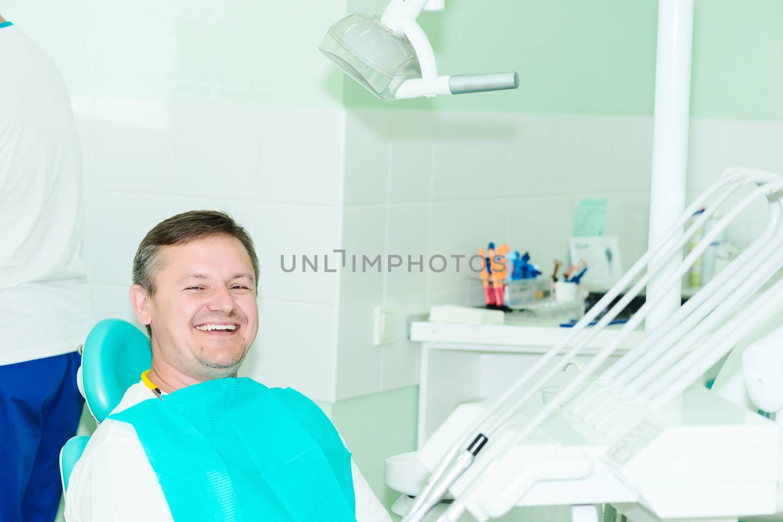 smiling patient looking at camera at the dentist office by Nanisimova