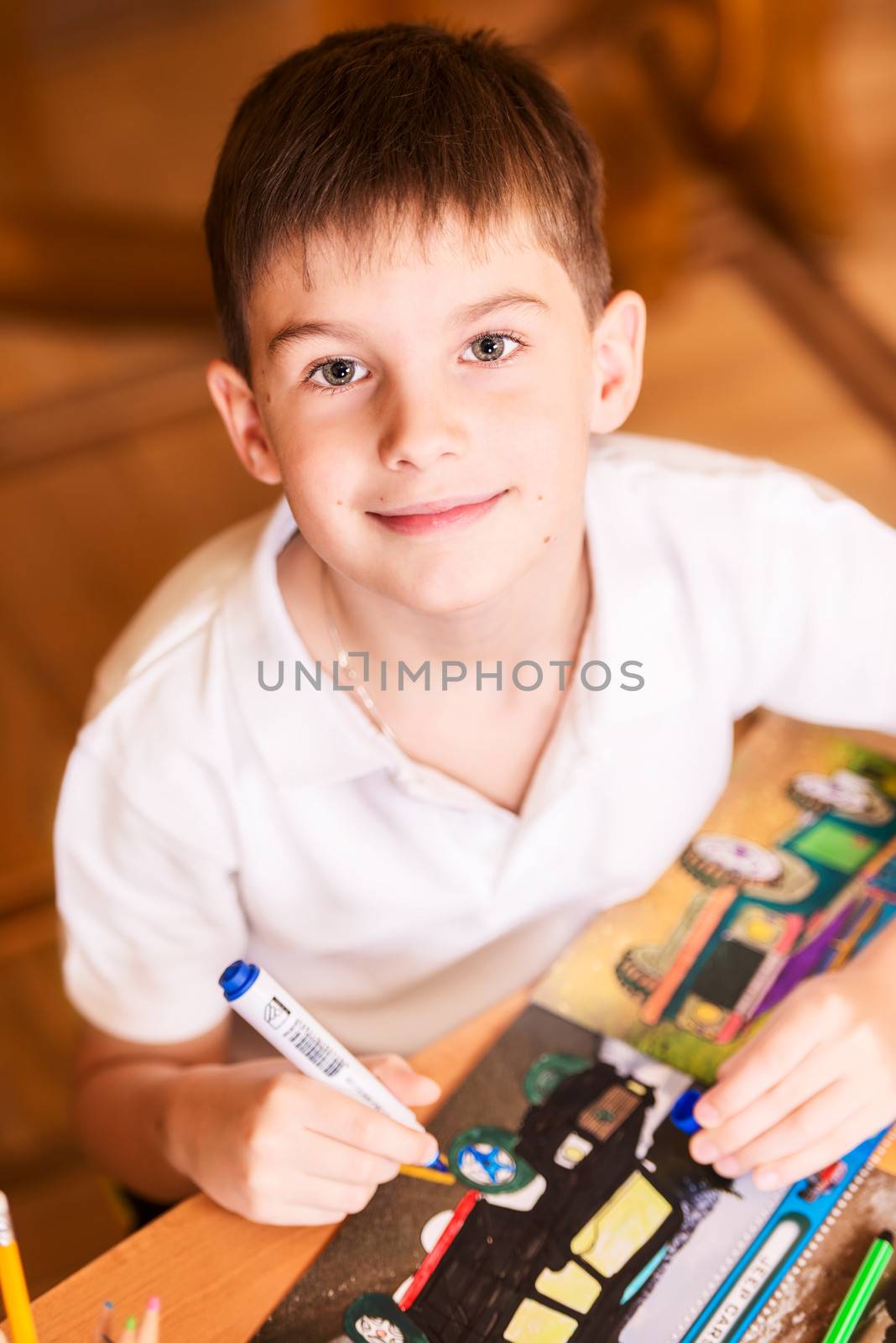 Boy colouring book looking at camera smiling