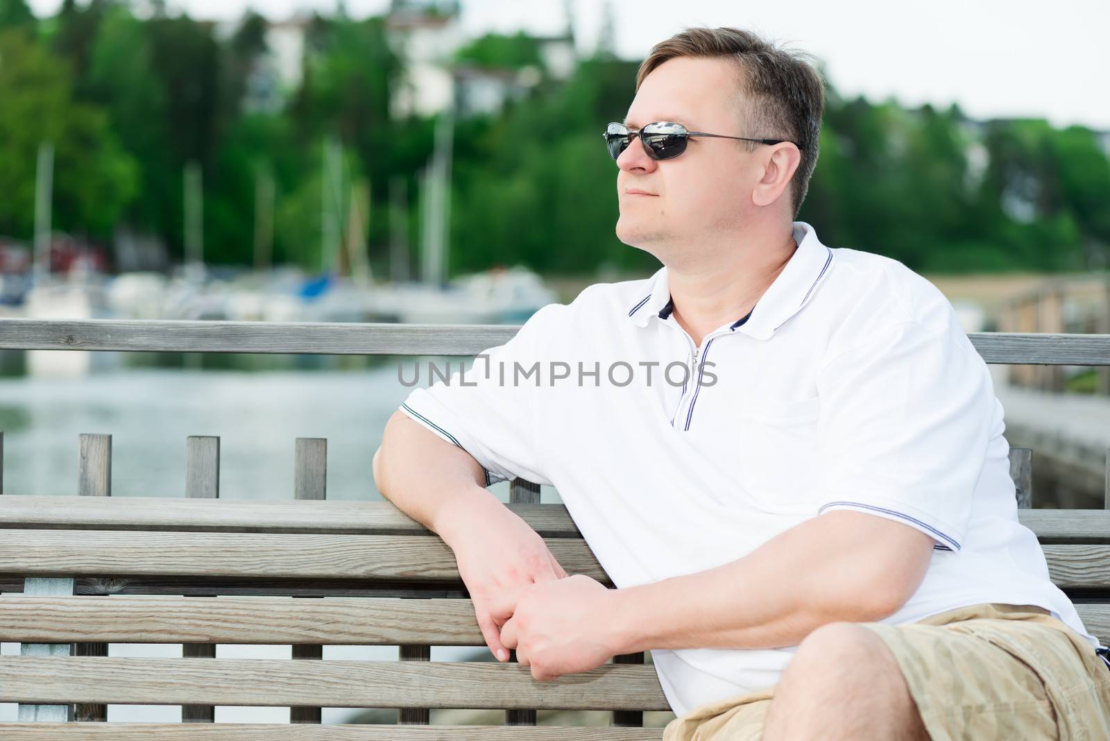 Middle aged men in sunglasses sitting on bench, looking away